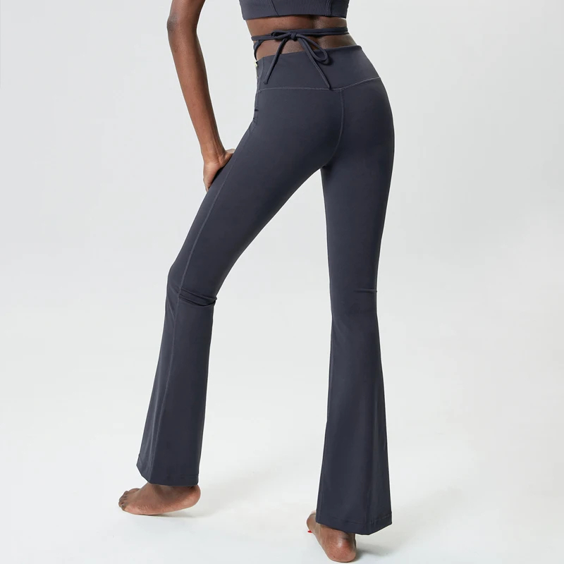 Back view of model wearing emerald flare yoga pants with tie-up waist, showcasing bell bottom design. Perfect for fashion-forward fitness.
